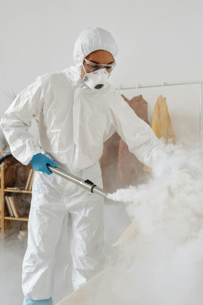 A professional in PPE disinfects an indoor space, emphasizing safety and hygiene.